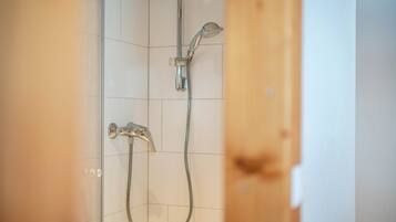 Eine Dusche mit Handbrause und wandmontiertem Wasserhahn.