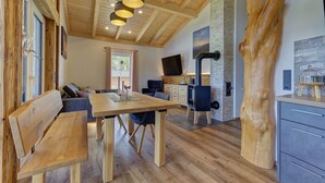 Un intérieur en bois comprenant une table à manger, des bancs, un canapé, un téléviseur et une cheminée.
