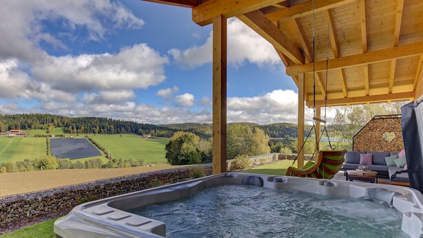 Un bain à remous avec vue sur un paysage verdoyant et un mur de pierres.