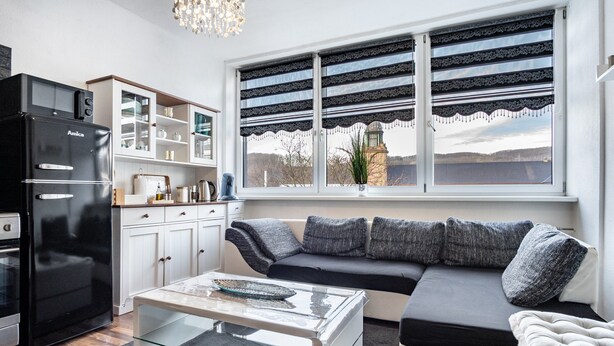 A modern kitchen with a black refrigerator, white cabinets, and a glass coffee table.