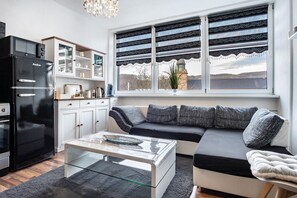 A modern kitchen with a black refrigerator, white cabinets, and a glass coffee table.