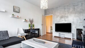A modern living room with a sofa, coffee table, TV, and decorative items.