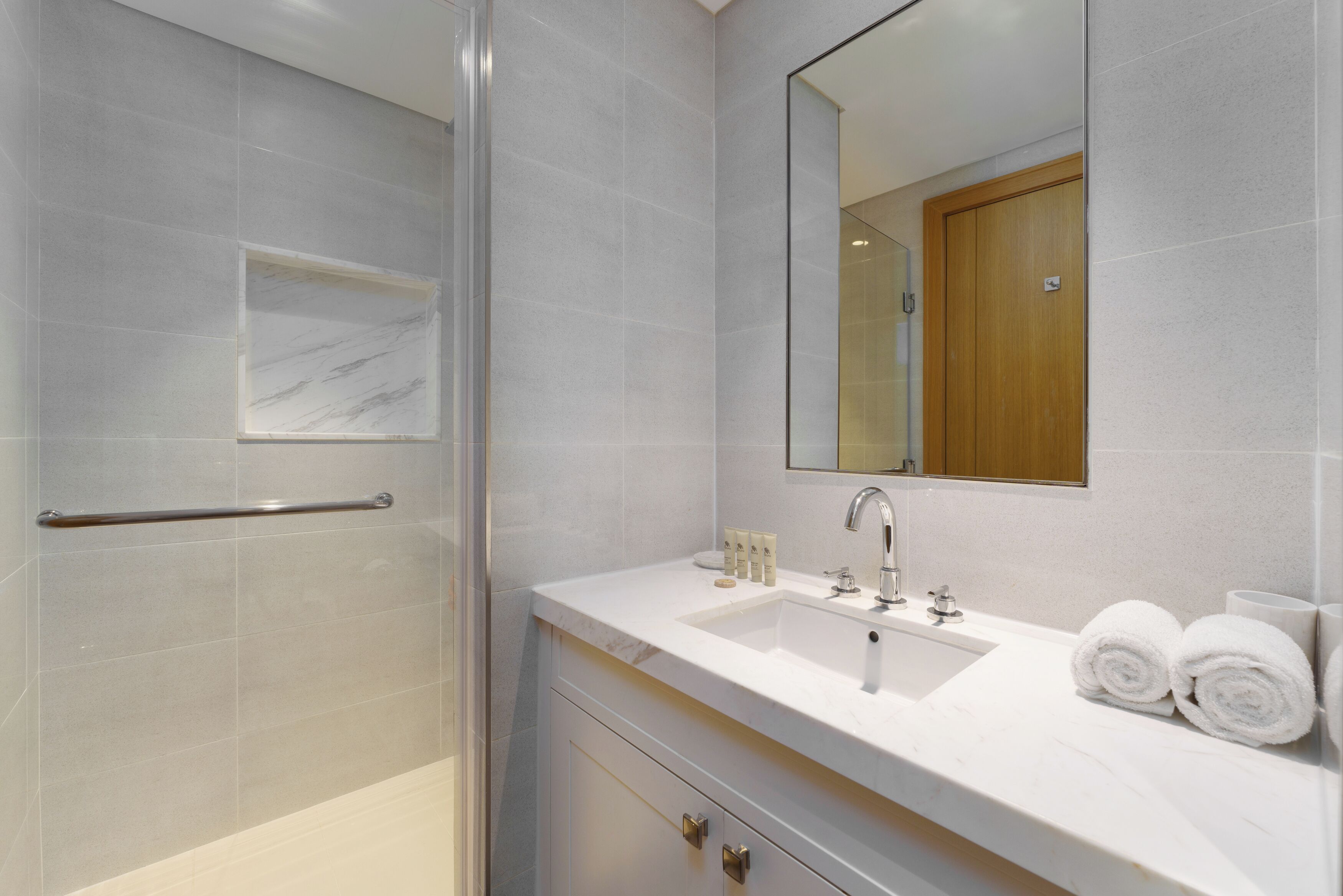 Une salle de bain avec un lavabo blanc, un miroir et un espace douche.