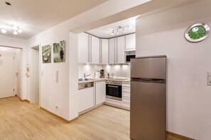 A modern kitchen with white cabinets, a stainless steel refrigerator, and a wall clock. - Apartment 'Ferienwohnung Viadukt' with Mountain View, Private Terrace and Wi-Fi (Willingen)