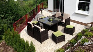 Eine Terrasse mit Korbmöbeln, einem Tisch und einem Sonnenschirm.