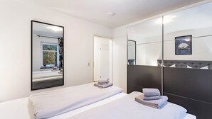 Et hotelværelse med to senge, et stort spejl og udsigt til en have.