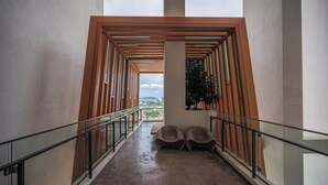 A corridor with a glass railing, a view of the city, and two seating areas. - HighPark Suites by Airhost (Petaling Jaya)