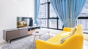 A modern living room with a yellow sofa, a TV on a cabinet, and a large window with curtains. - HighPark Suites by Airhost (Petaling Jaya)