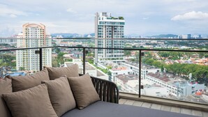 A balcony with a sofa and cushions, overlooking a cityscape with modern buildings and a clear sky. - HighPark Suites by Airhost (Petaling Jaya)