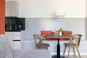 Een moderne keuken met een eethoek, inclusief een tafel met stoelen, een bank en een hangende lamp.