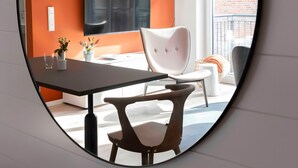 Een moderne eetruimte met een tafel, stoelen en een aan de muur bevestigde televisie.