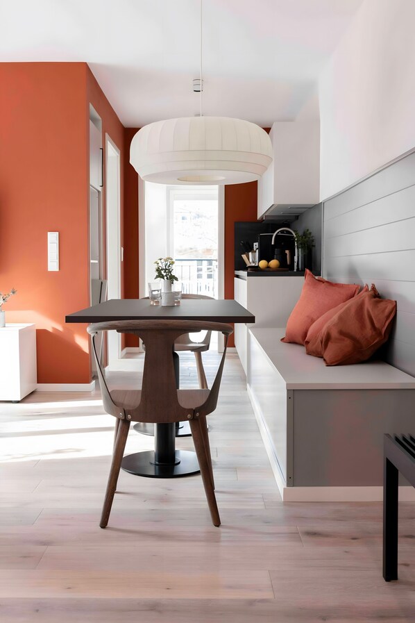A modern kitchen with a dining area, featuring a table, chairs, and a bench.