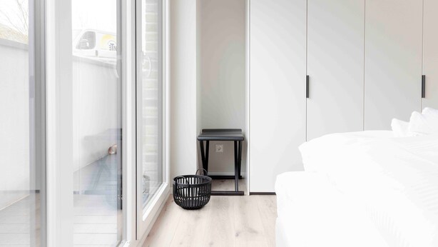 Une chambre à coucher avec un lit, une petite table, un panier et une armoire.