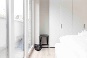 Un dormitorio con cama, una mesita, una cesta y un armario.