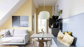 A modern living space with a dining area, a sofa, a table, and a kitchen area. - Apartment 'Ocean Star' with Balcony and Wi-Fi (Sankt Peter-Ording)