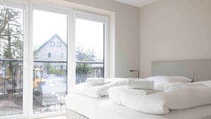 Une chambre avec un grand lit, une table de chevet et une fenêtre donnant sur un bâtiment et sur des travaux de construction à l’extérieur.