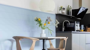 Una cocina moderna con una mesa redonda y dos sillas, un florero blanco con flores y una encimera negra.