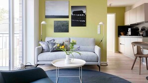 A modern living room with a sofa, a coffee table with flowers, and artwork on the wall. - Apartment 'Sunseeker' with Balcony and Wi-Fi (Sankt Peter-Ording)