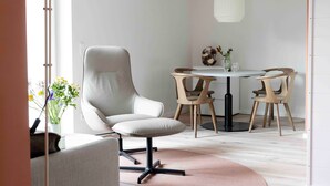 A modern dining area with a round table, four chairs, a single chair, a floor lamp, and a vase with flowers. - Apartment 'Invictus' with Private Terrace and Wi-Fi (Sankt Peter-Ording)