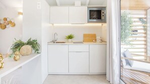 Ett modernt kök med vita skåp, en inbyggd mikrovågsugn och ett fönster med utsikt över grönområden.