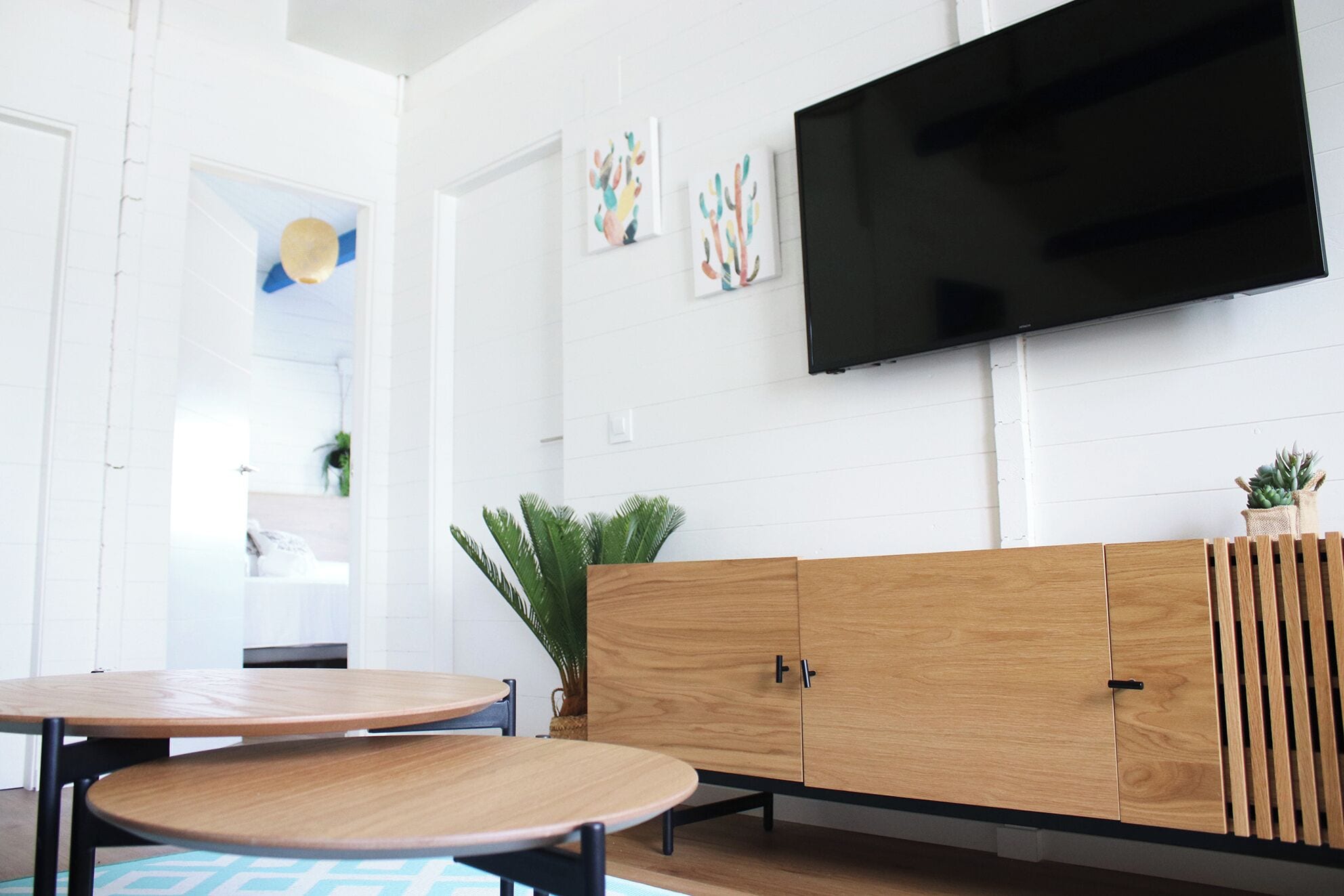 A modern living room with a wooden cabinet, a flat-screen TV, and a round table.