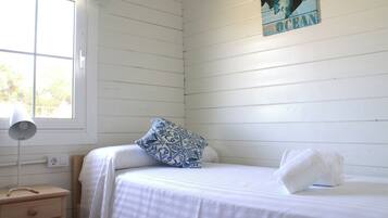 Un dormitorio con una cama, una mesita de noche, una lámpara y una ventana.