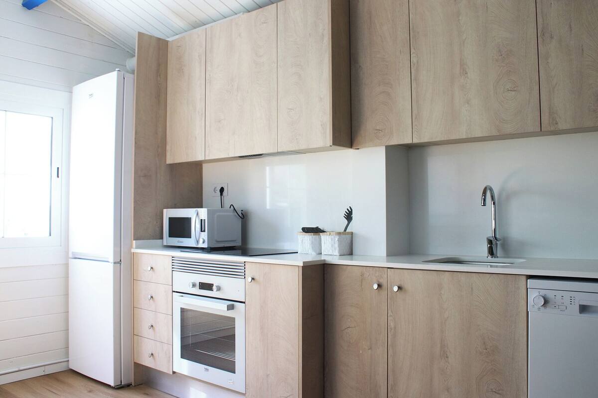 A modern kitchen with wooden cabinets, a microwave, an oven, and a dishwasher.