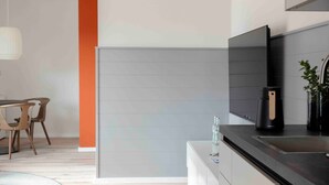 A modern kitchen with a black countertop, white cabinets, and a grey backsplash. - Apartment 'Quicksilver' with Balcony and Wi-Fi (Sankt Peter-Ording)