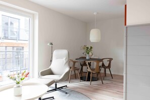 Una habitación moderna con una mesa redonda, una silla blanca, una lámpara colgante y vistas al exterior.
