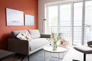 Un salón moderno con un sofá, una mesa redonda de centro y vistas al exterior a través de amplios ventanales.