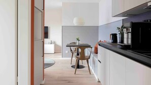A modern kitchen with a dining area, wooden flooring, and a pendant light. - Apartment 'Orkney' with Balcony and Wi-Fi (Sankt Peter-Ording)