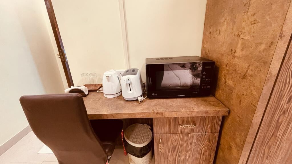 A small kitchenette with a microwave, toaster, and coffee maker on a wooden countertop.