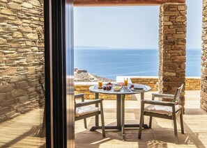 A table with a view of the sea, stone walls, and a bench. - Dolce Villa Tinos Kardiani in Stone & Sunset Views (Kardiani)