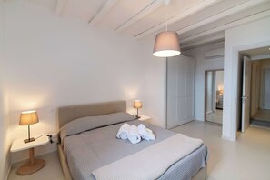 A modern bedroom with a large bed, two bedside lamps, and a hanging light fixture. - Dolce Villa Tinos Kardiani in Stone & Sunset Views (Kardiani)