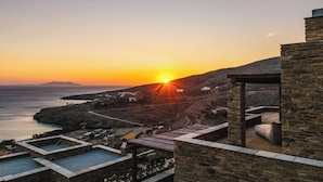 Ein Küstenresort mit Steinarchitektur, einem Schwimmbad und Blick auf den Sonnenuntergang.