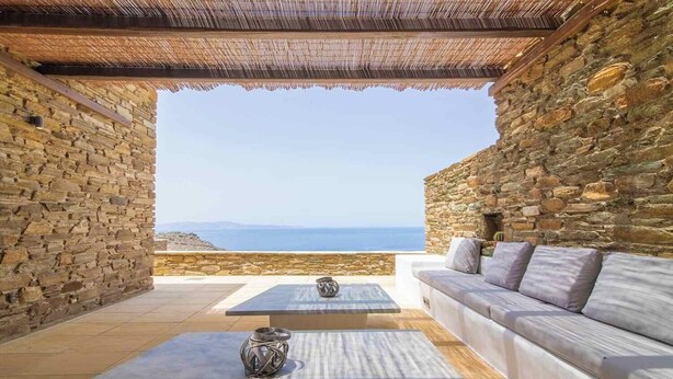 Ein Zimmer mit Steinwänden und Blick auf das Meer, mit einer Couch und einem Tisch.