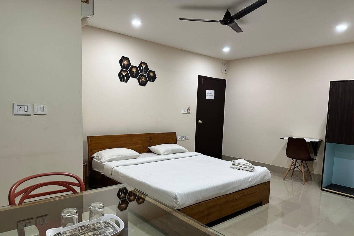 Ein Hotelzimmer mit einem Bett, einem Schreibtisch mit Stuhl, einem Deckenventilator und einer Tür mit Schild.