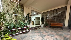 An indoor space with a tiled floor, potted plants, a bench, and a wall with a grid pattern. - The Dew Drop Hotel (Guwahati)