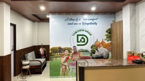 A reception area with a wooden ceiling, a reception desk, a sofa, and a poster advertising The Dew Drop. - The Dew Drop Hotel (Guwahati)
