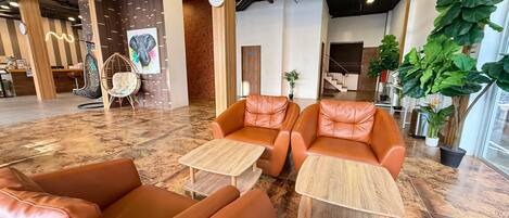 A modern lobby with leather sofas, wooden tables, and potted plants.
