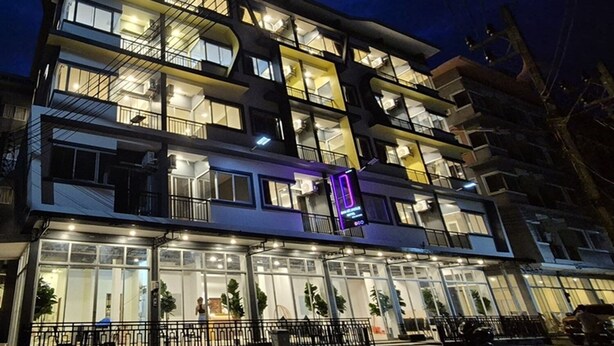 A multi-story hotel with balconies, large windows, and a well-lit facade.