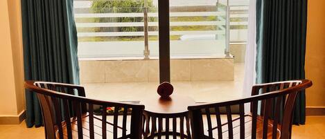 Una habitación con vista al mar, un balcón con barandilla y dos sillas de madera.
