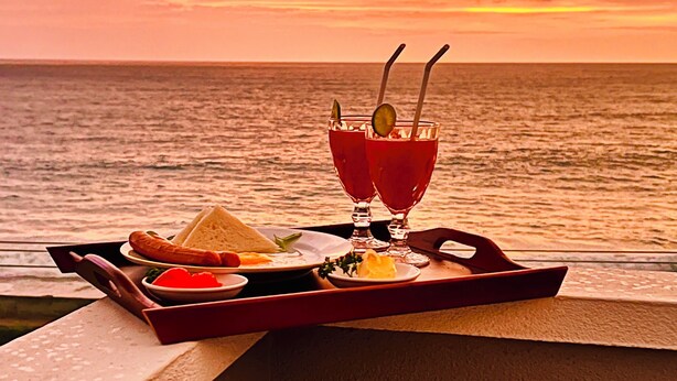 A sunset view with a tray of food and drinks on a balcony. - Ocean Front Villa (Hikkaduwa)
