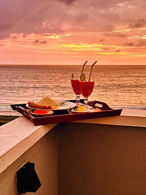 A sunset view with a tray of food and drinks on a balcony. - Ocean Front Villa (Hikkaduwa)