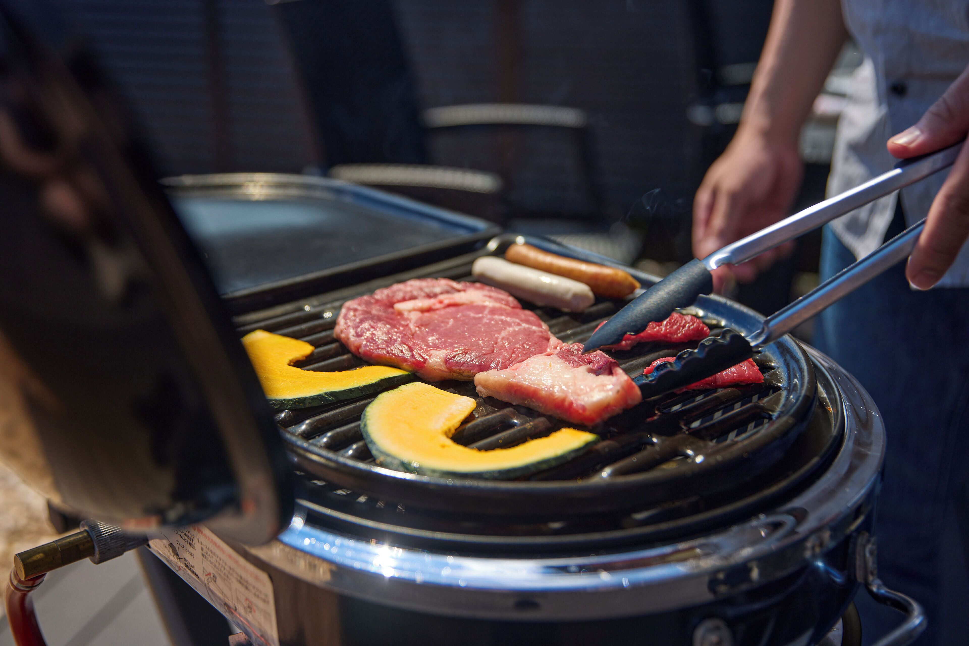 A grill with various meats and vegetables being cooked.