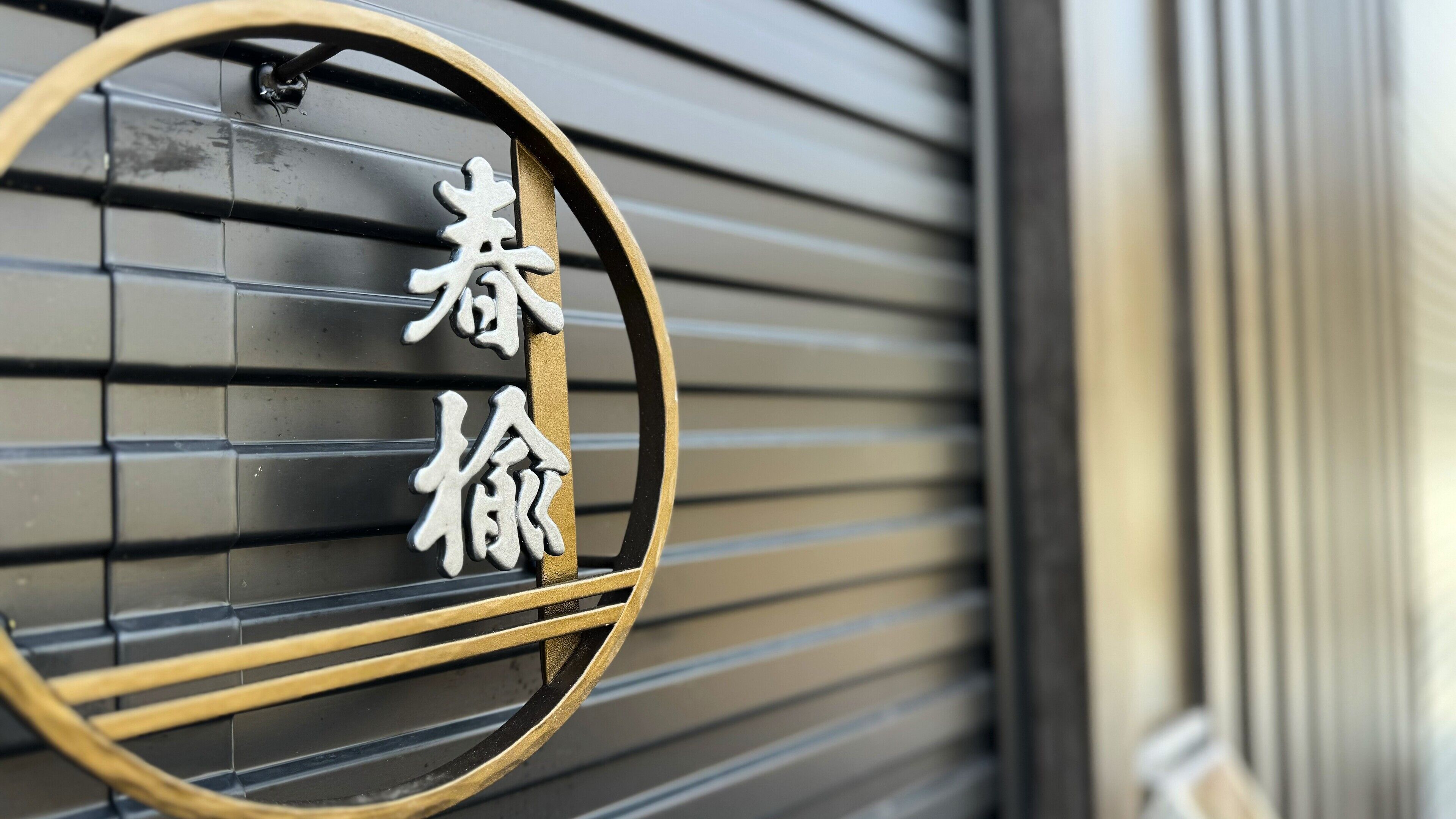 A metal sign with Chinese characters on a building's shutter.