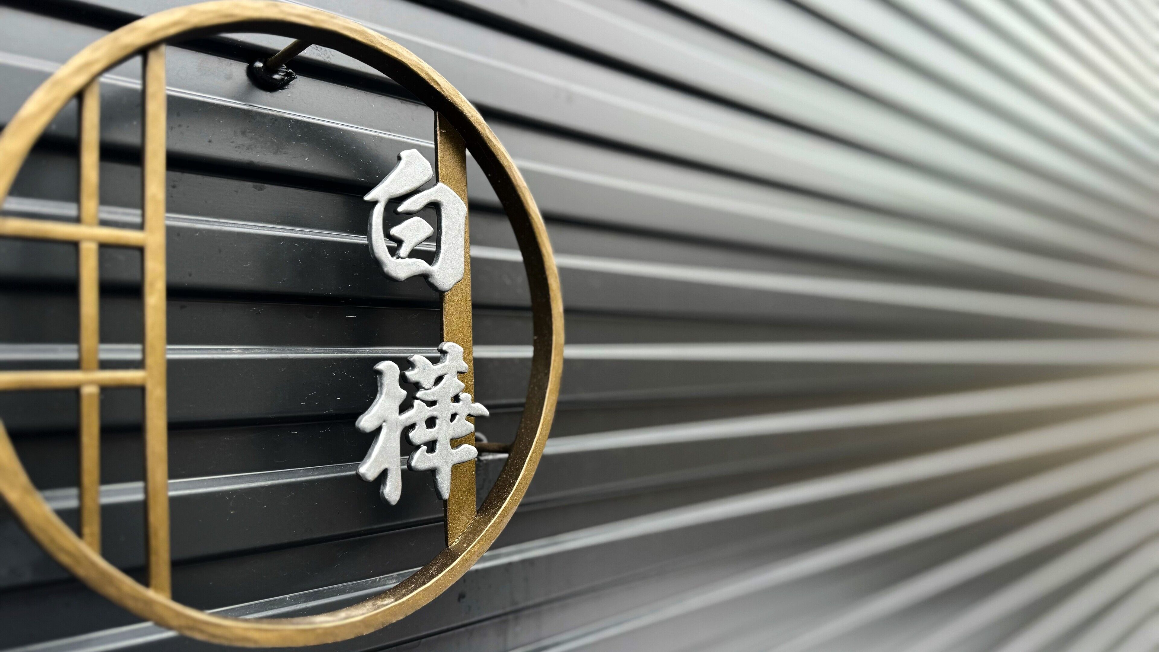 A close-up of a metal sign with Chinese characters, mounted on a curved metal structure.