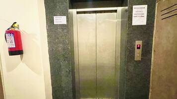 Un ascensor con un cartel de capacidad máxima, un extintor y un panel de control.