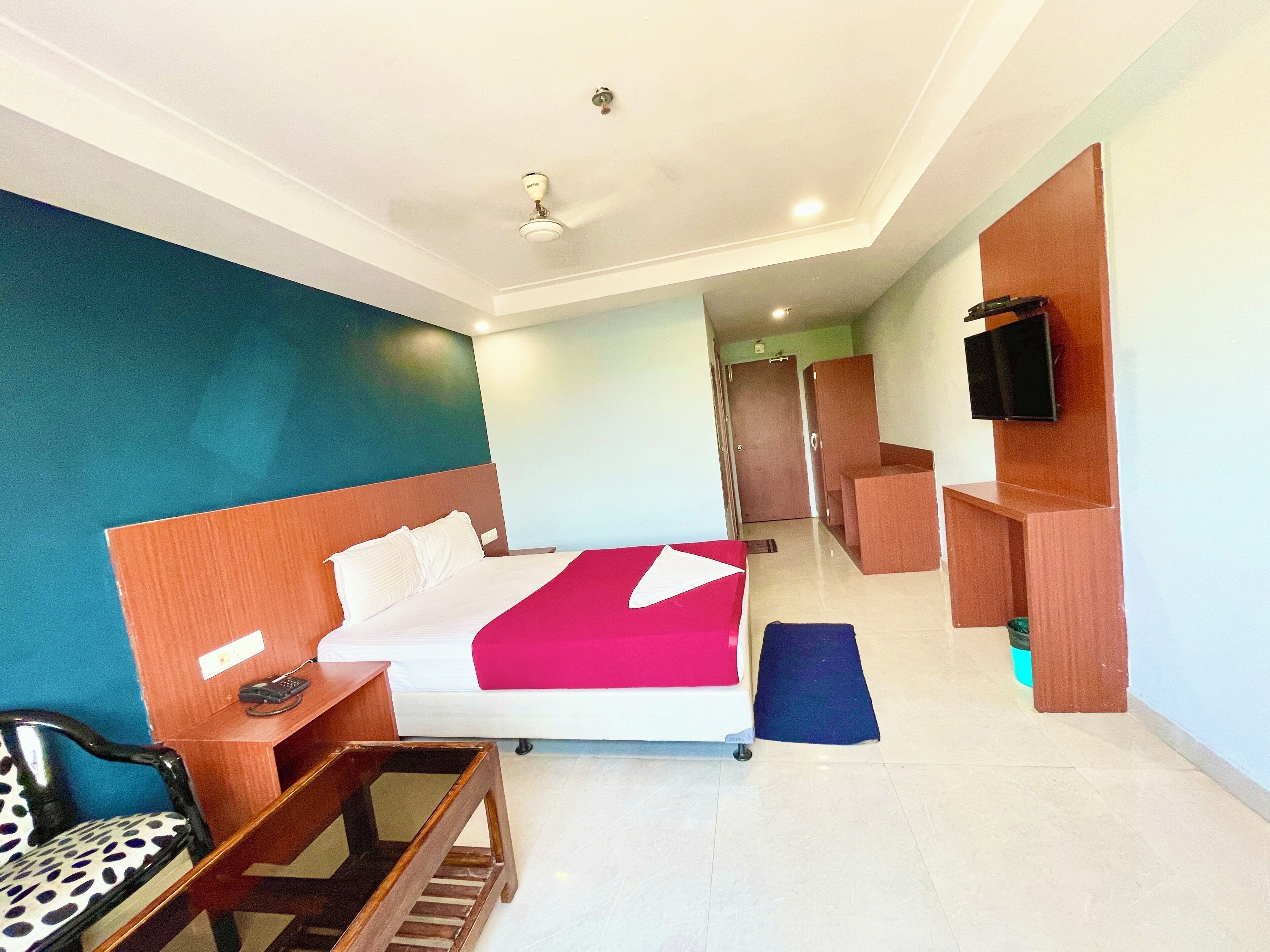 Habitación de hotel con cama, escritorio, silla, televisión y baño a la vista.