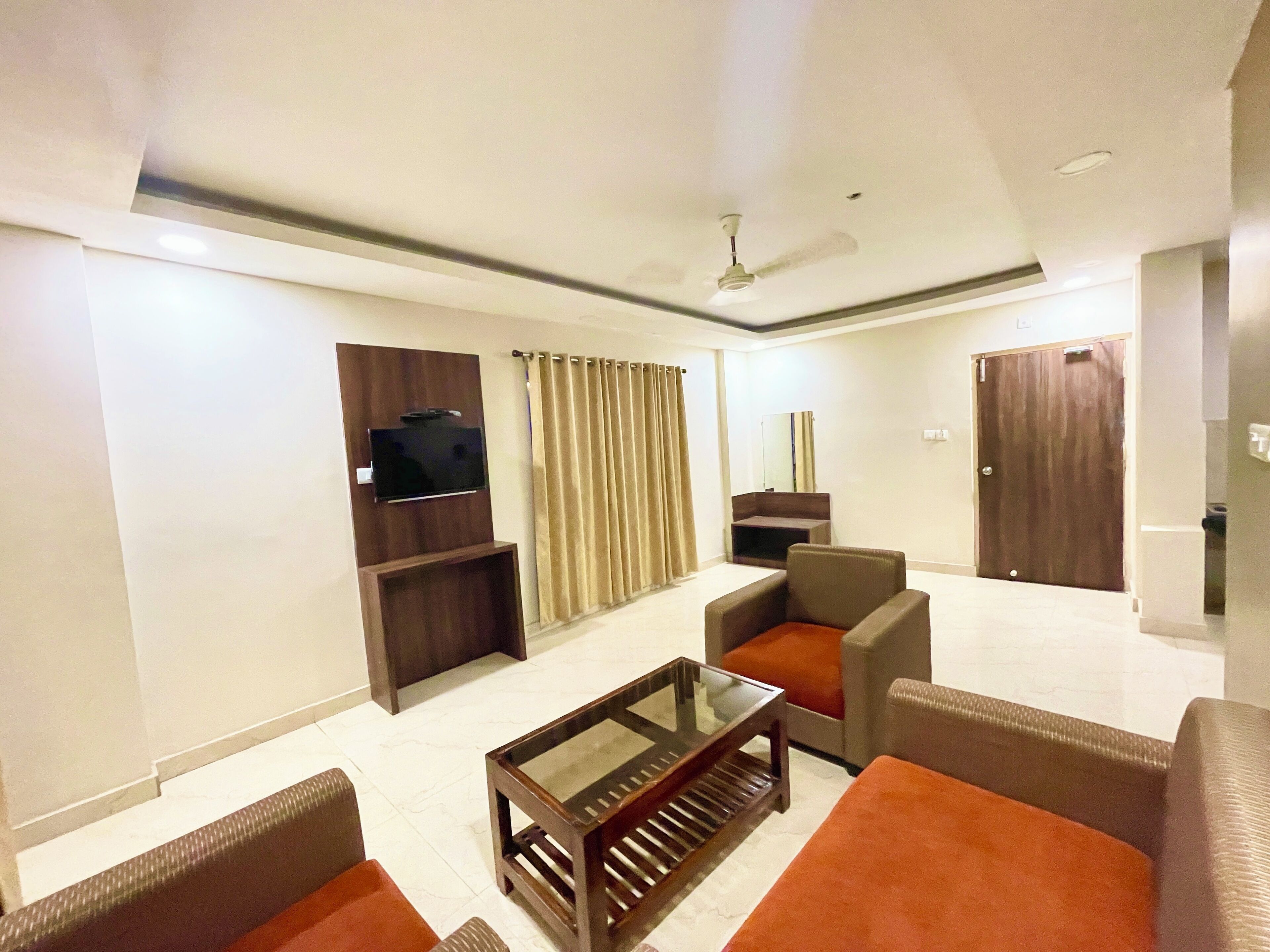 A modern living room with a flat-screen TV, a glass coffee table, and comfortable seating.